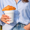 Café à emporter avec couvercle et croissant par dessus