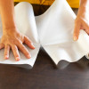 Tête-à-tête en spunbond blanc en rouleau prédécoupé 0,40 x 48 m pour une décoration de table élégante avec chemins de table et housses de chaises assortis, accompagné d'un set de table noir en spunbond de 30x40cm.